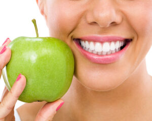 Frau mit einem strahlenden Lächeln und einem Apfel